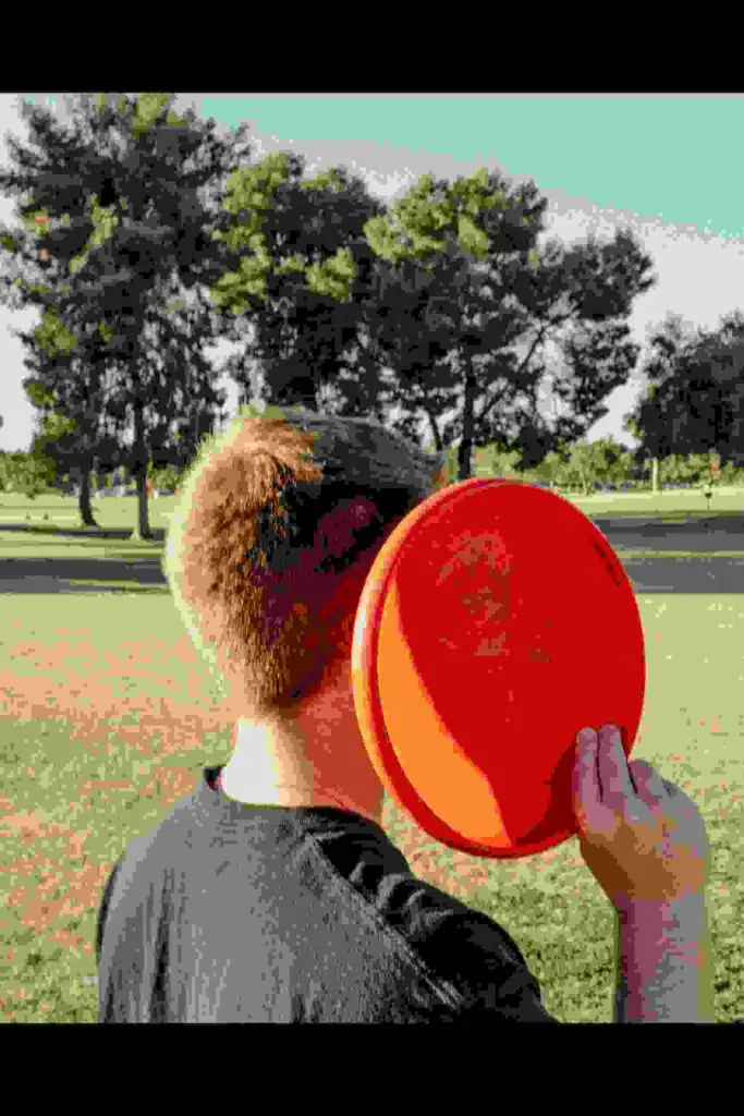 A young man playing disc golf throwing a disc.
