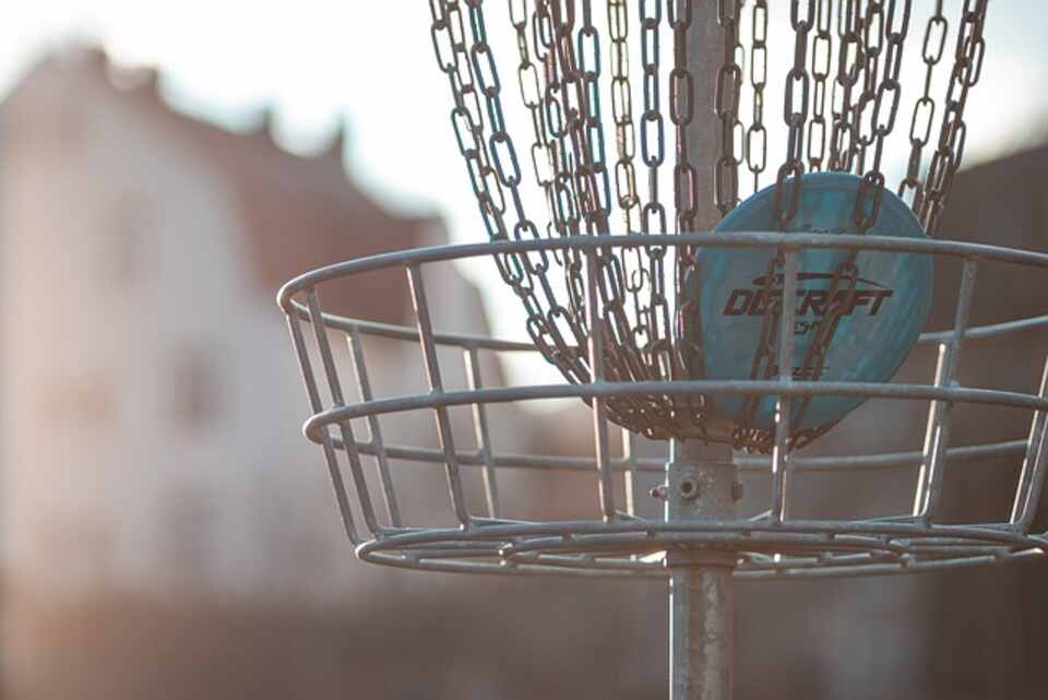 A metal disc golf basket in a park.
