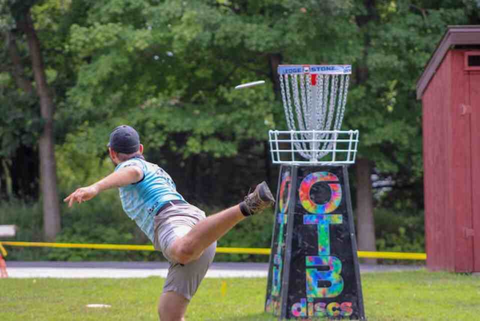 A person taking a disc golf shot at a basket.