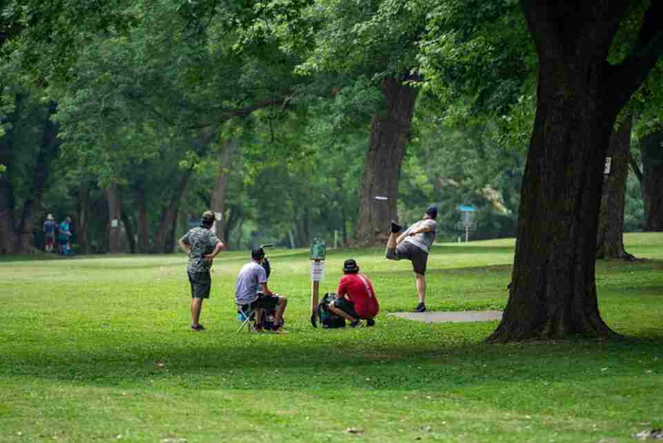 A group of people practicing shots in disc golf.