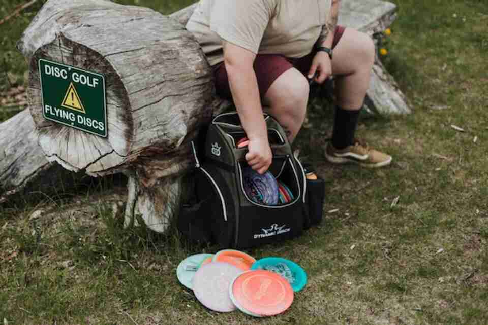 A man removing disc golf discs from his backpack.
