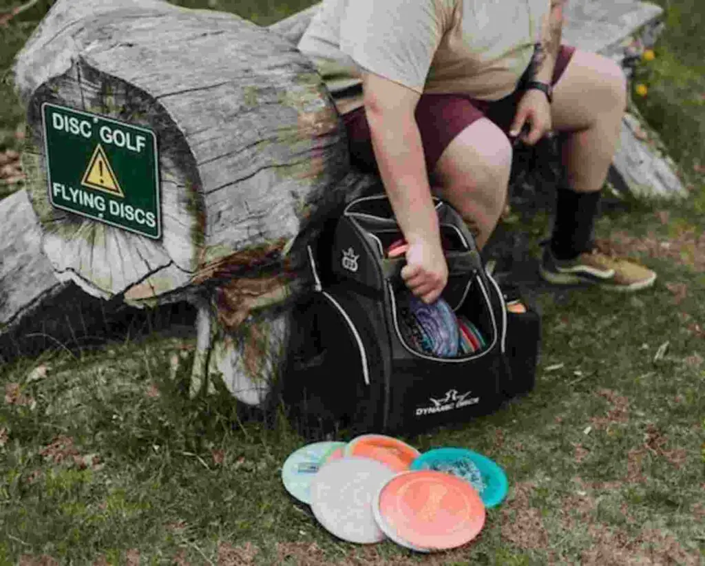 A man with a bag of discs getting ready to play disc golf.